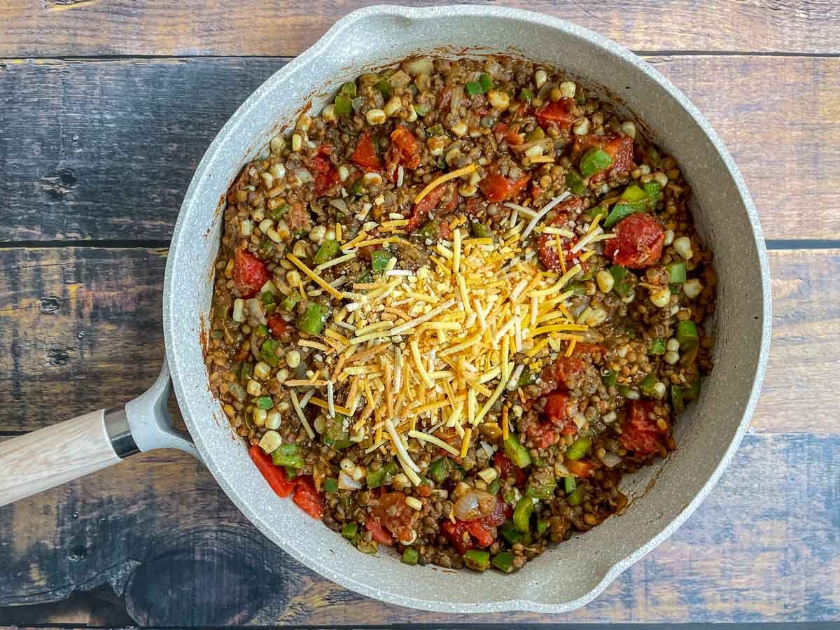 Diced tomatoes, corn, and vegan cheese added to vegan taco skillet.