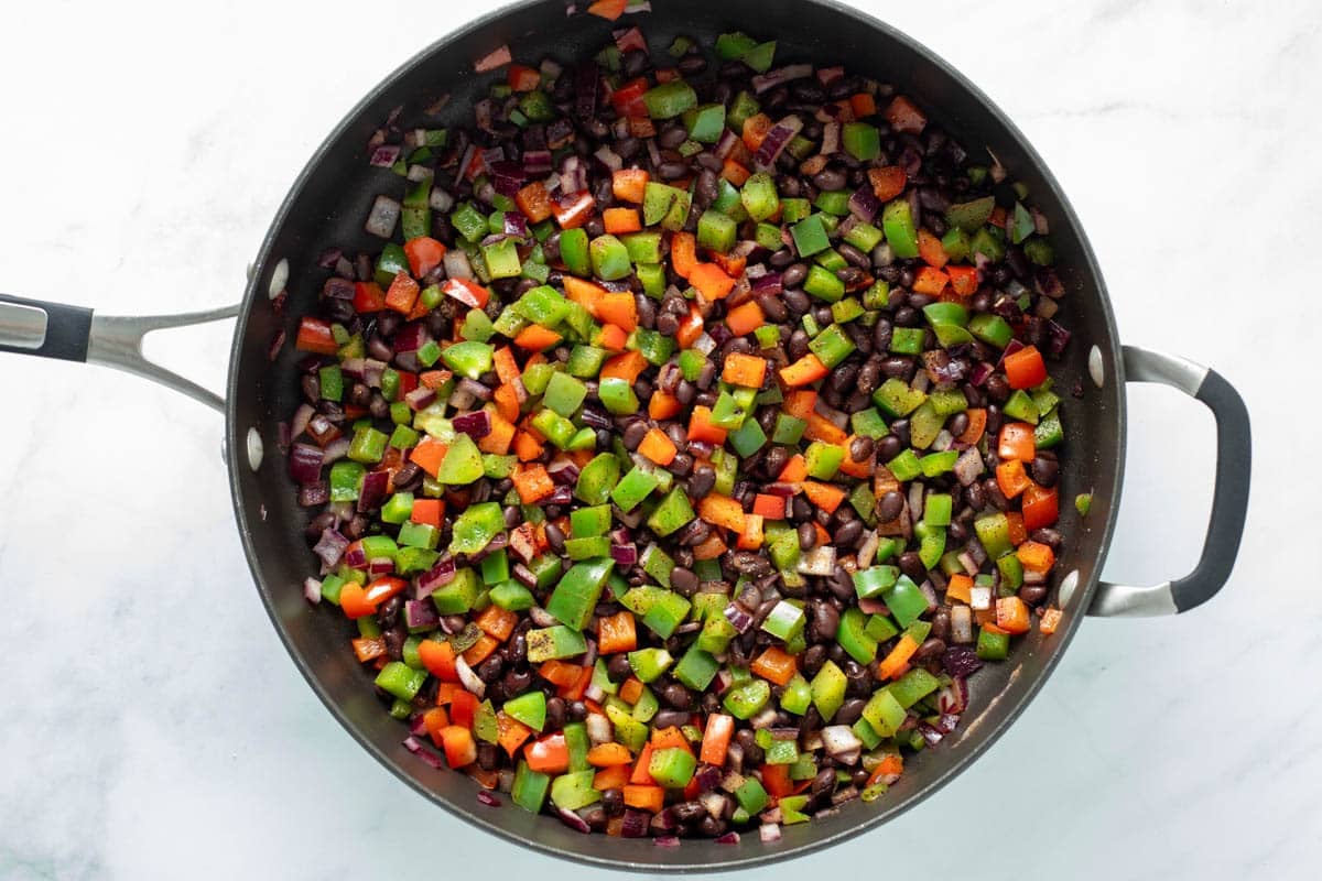 Diced peppers, onions, and black beans in saute pan.
