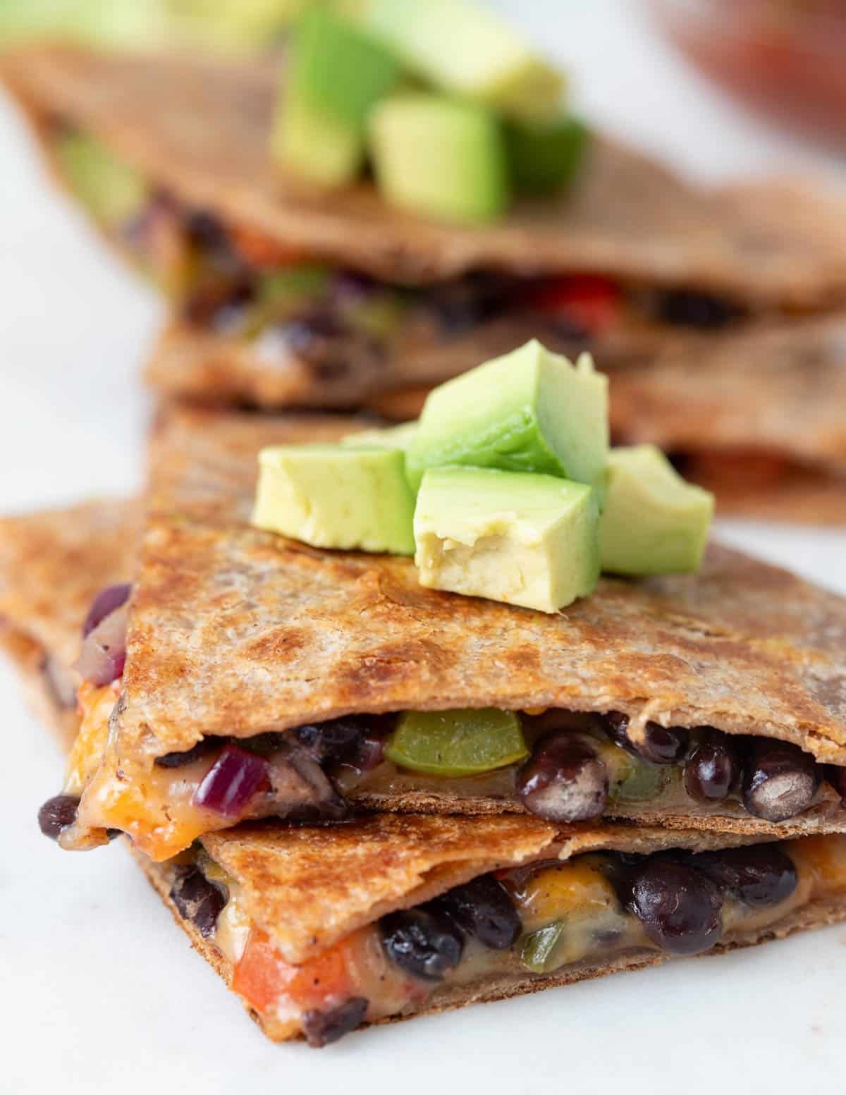 Vegan quesadilla triangles topped with diced avocado.
