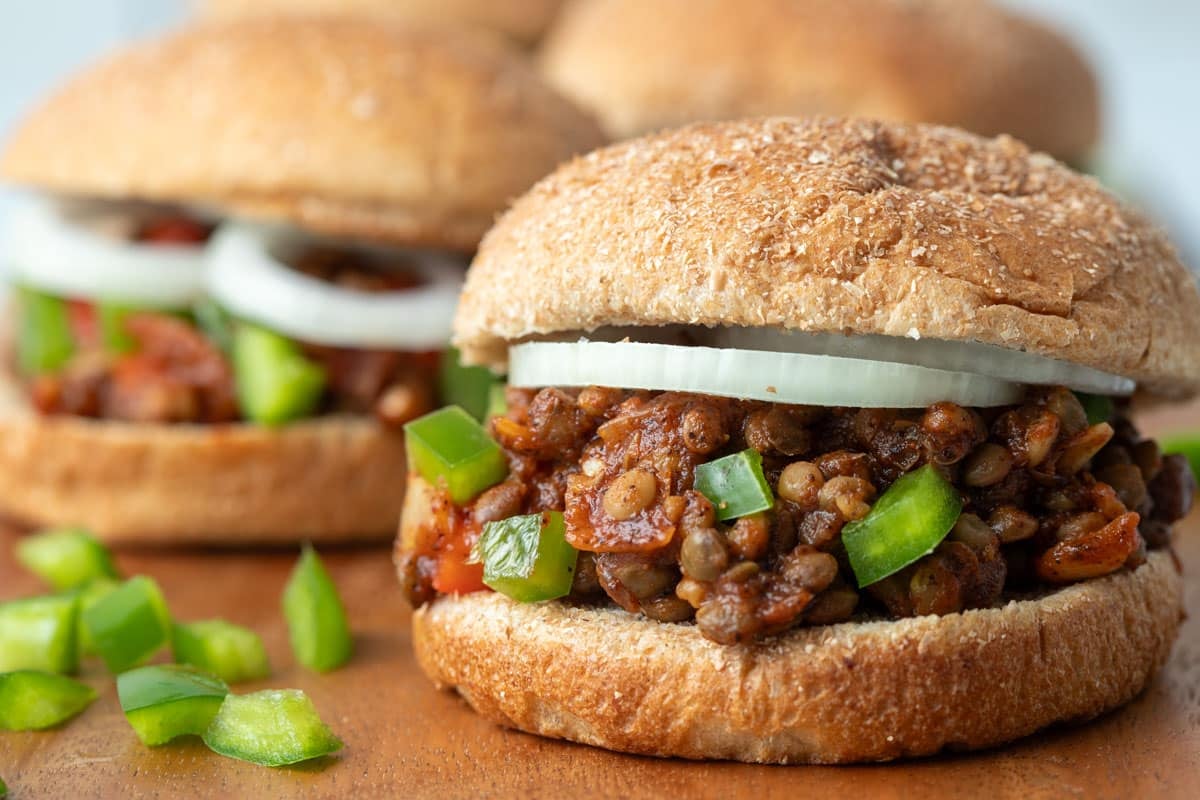 Vegan sloppy joes on a cutting board served on whole wheat buns.