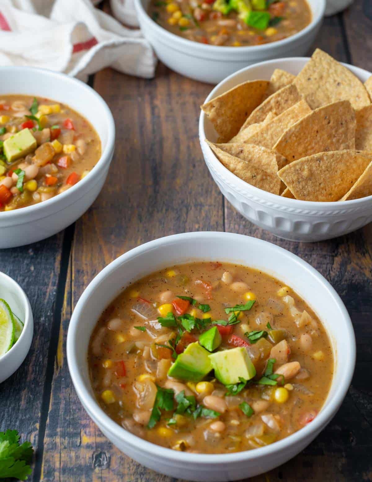 Bowls of vegan white bean chili served with a side of tortilla chips.
