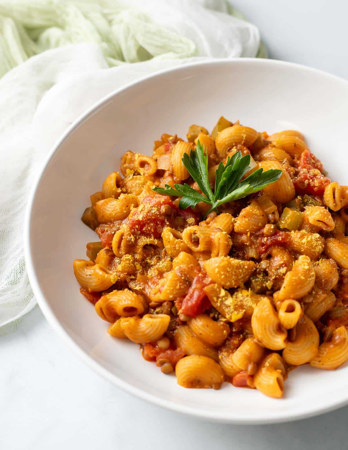 Vegan hamburger helper in a wide white bowl topped with parsley.
