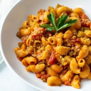 Vegan hamburger helper in a wide white bowl topped with parsley.