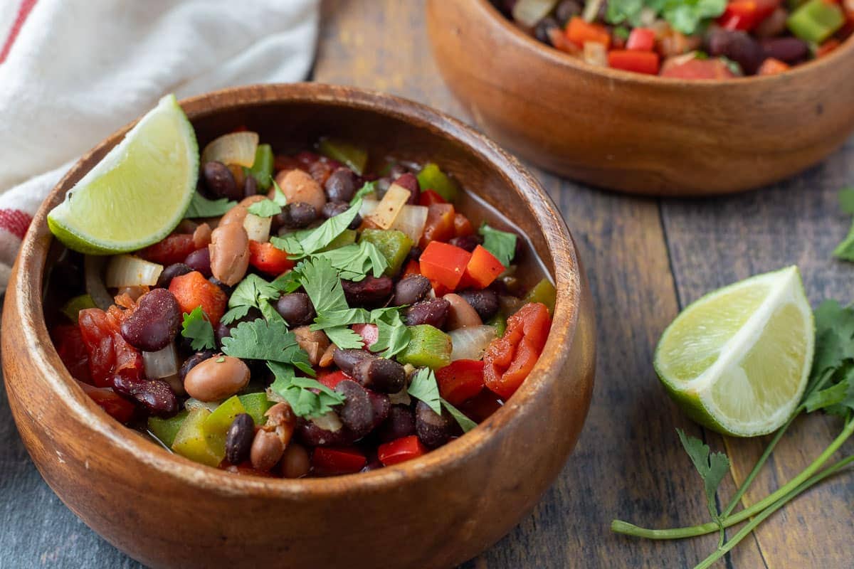 Bowl of three bean chili served with a wedge of lime. 