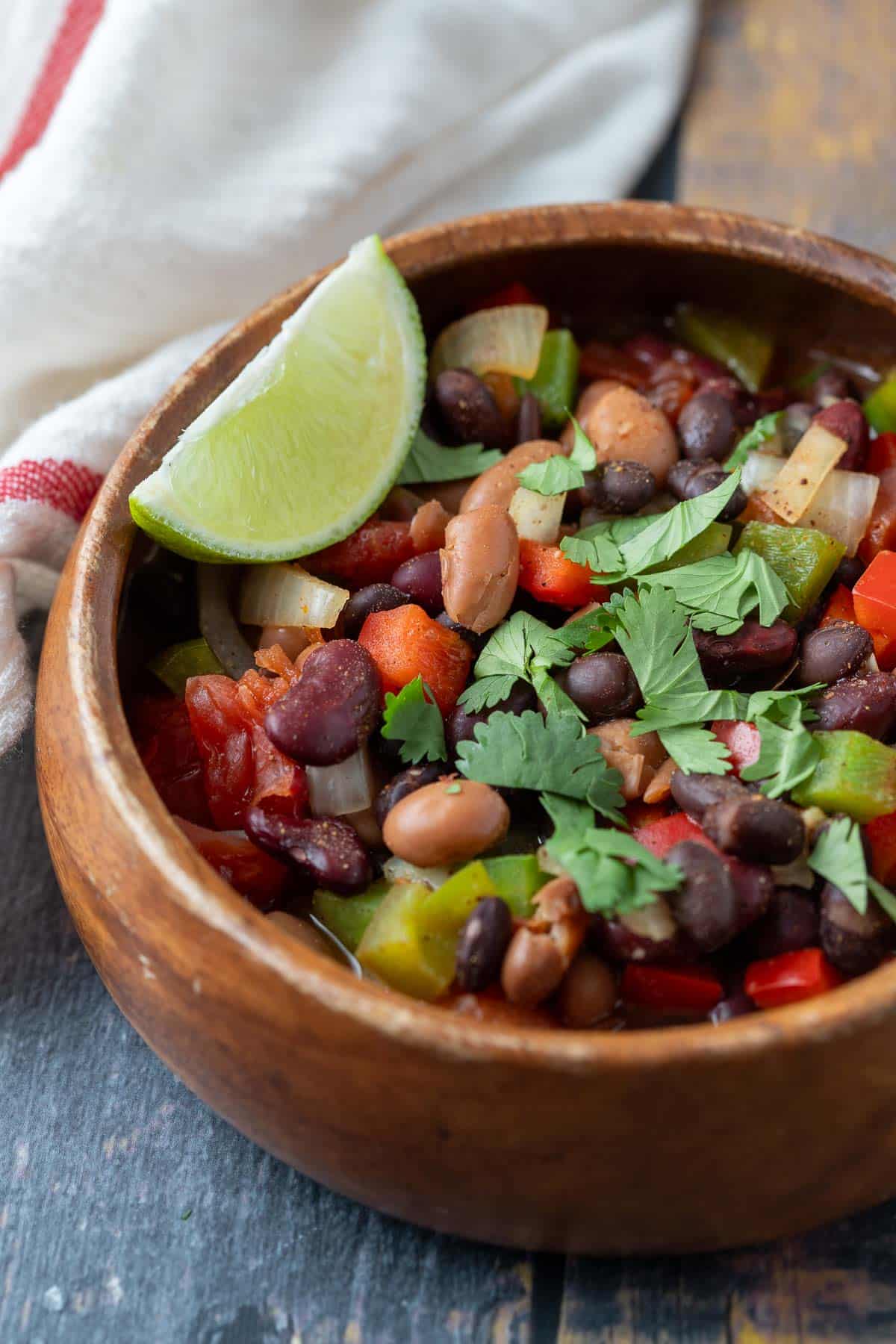 Bowl of three bean chili topped with fresh herbs.