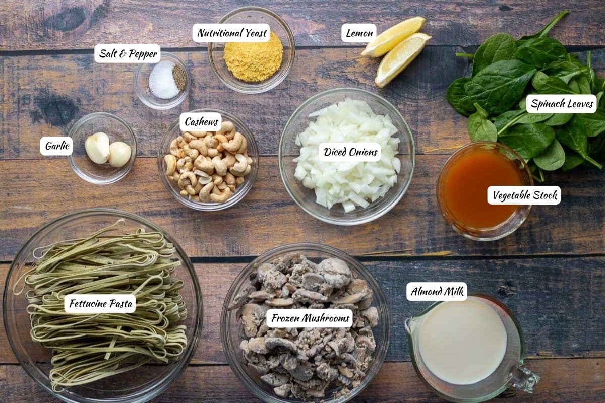 Vegan mushroom pasta ingredients: salt and pepper, nutritional yeast, lemon, spinach, vegetable stock, almond milk, frozen mushrooms, pasta, cashews, garlic.