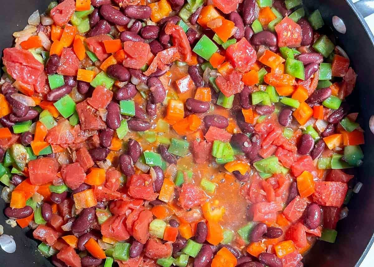 Red beans, bell peppers, and diced tomatoes cooking in large saute pan.