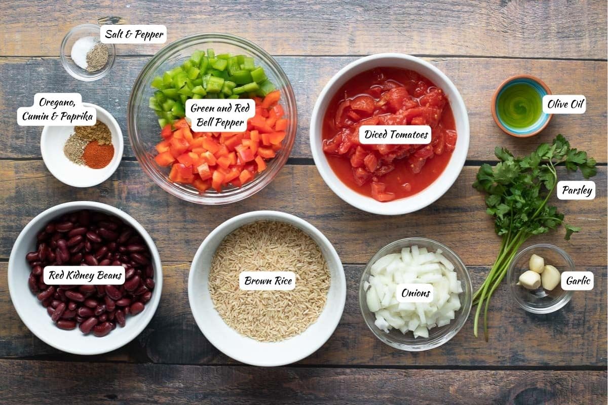Ingredients for red beans and rice: salt, pepper, spices, green and red bell pepper, diced tomatoes, olive oil, parsley, garlic, onions, brown rice, red kidney beans.