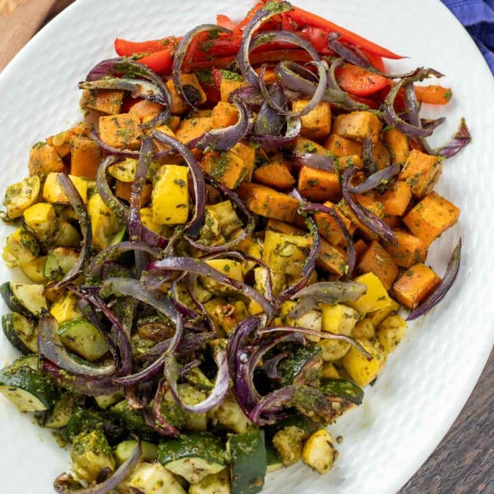 Plate of rainbow roasted vegetables with pesto.
