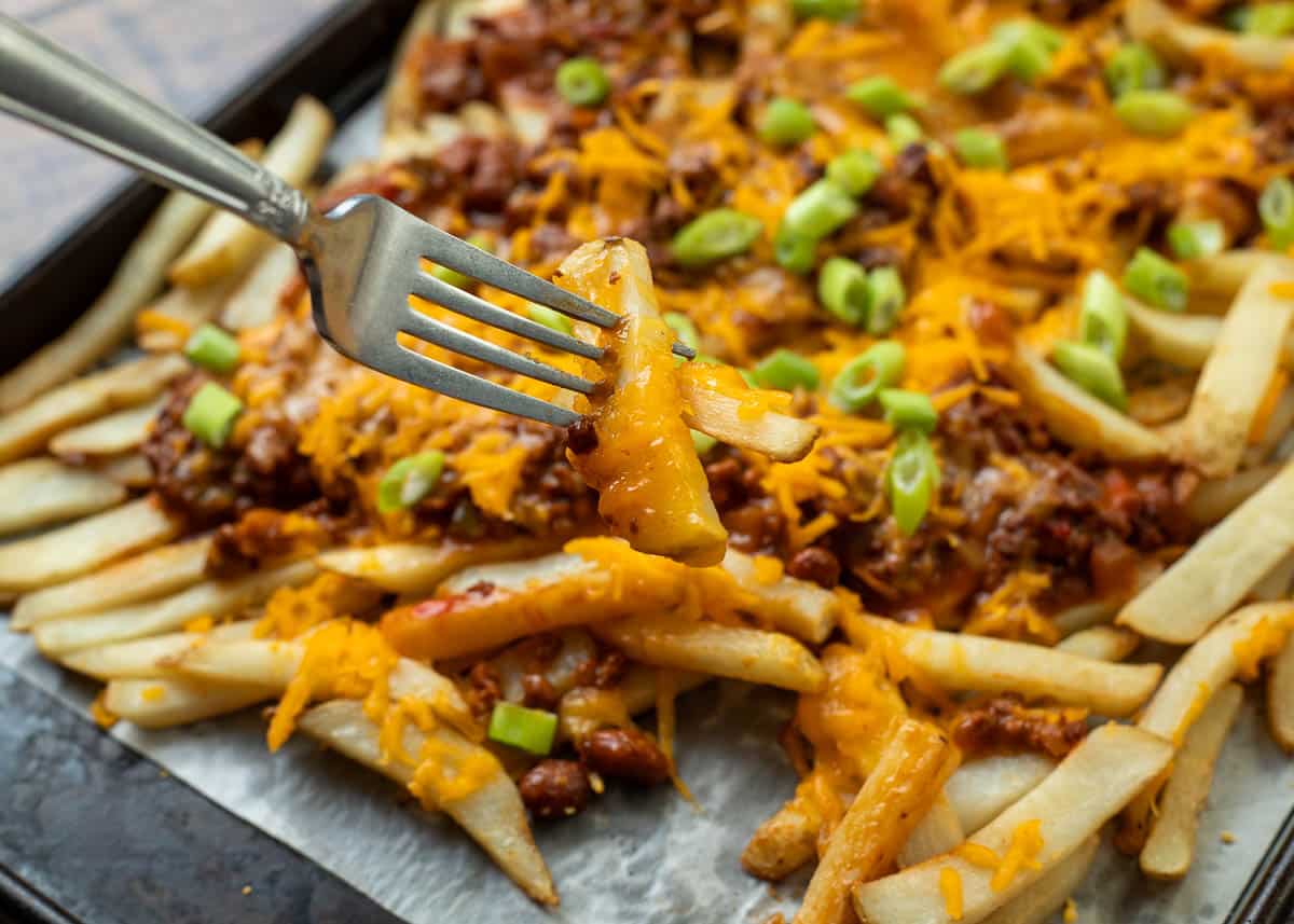 Fork digging into sheet pan of vegan dirty fries.