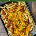 Vegan Dirty Fries: sheet pan of fries topped with vegan chili, vegan cheese, and scallions.
