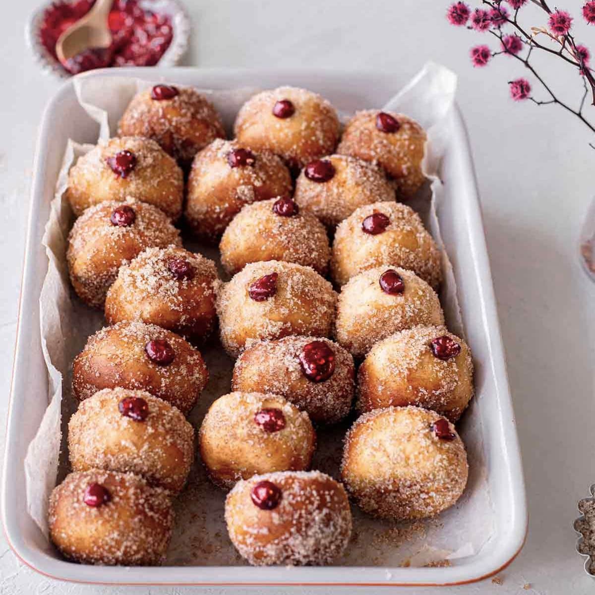 Jelly filled donuts tossed in sugar and on display in a casserole dish.
