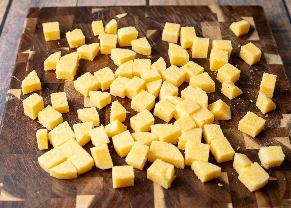 Polenta cut into cubes on a cutting board.