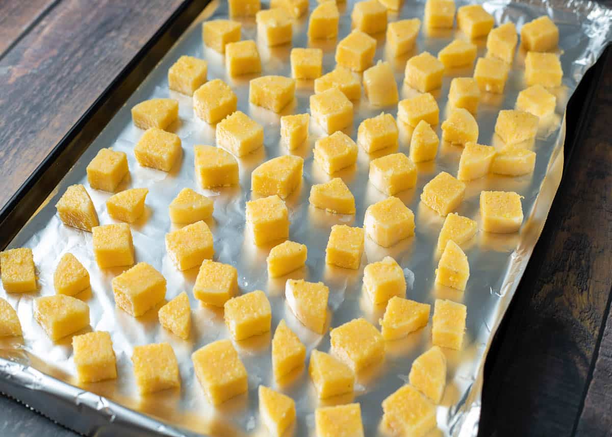 Polenta cubes on a baking sheet lined with aluminum foil.