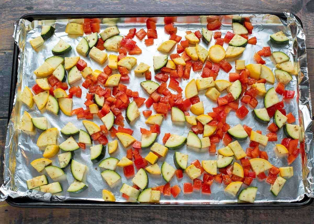 Diced vegetables on a baking sheet lined with aluminum foil.
