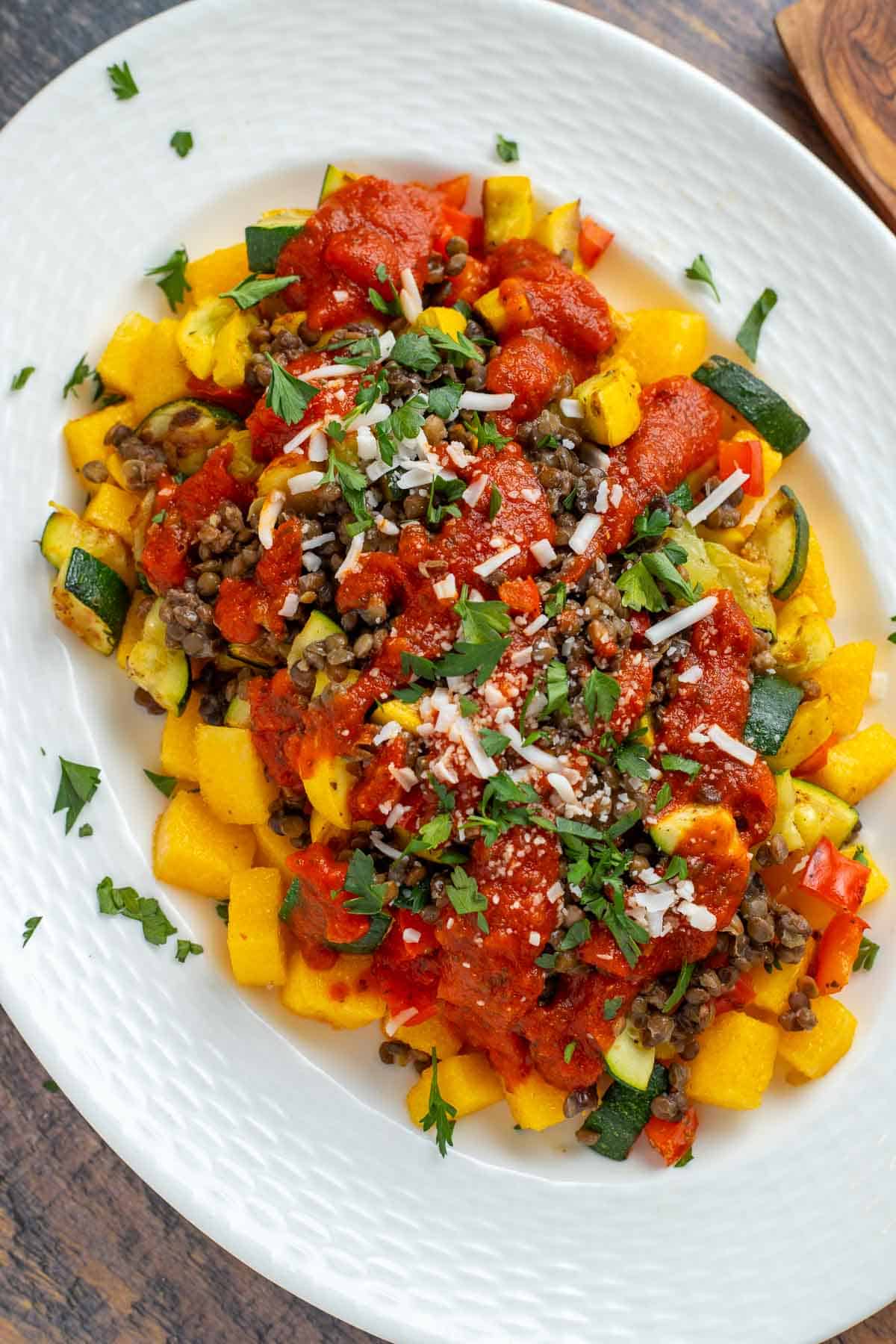 Crispy baked polenta topped with roasted vegetables, lentils, marinara sauce, vegan mozzarella and parsley.