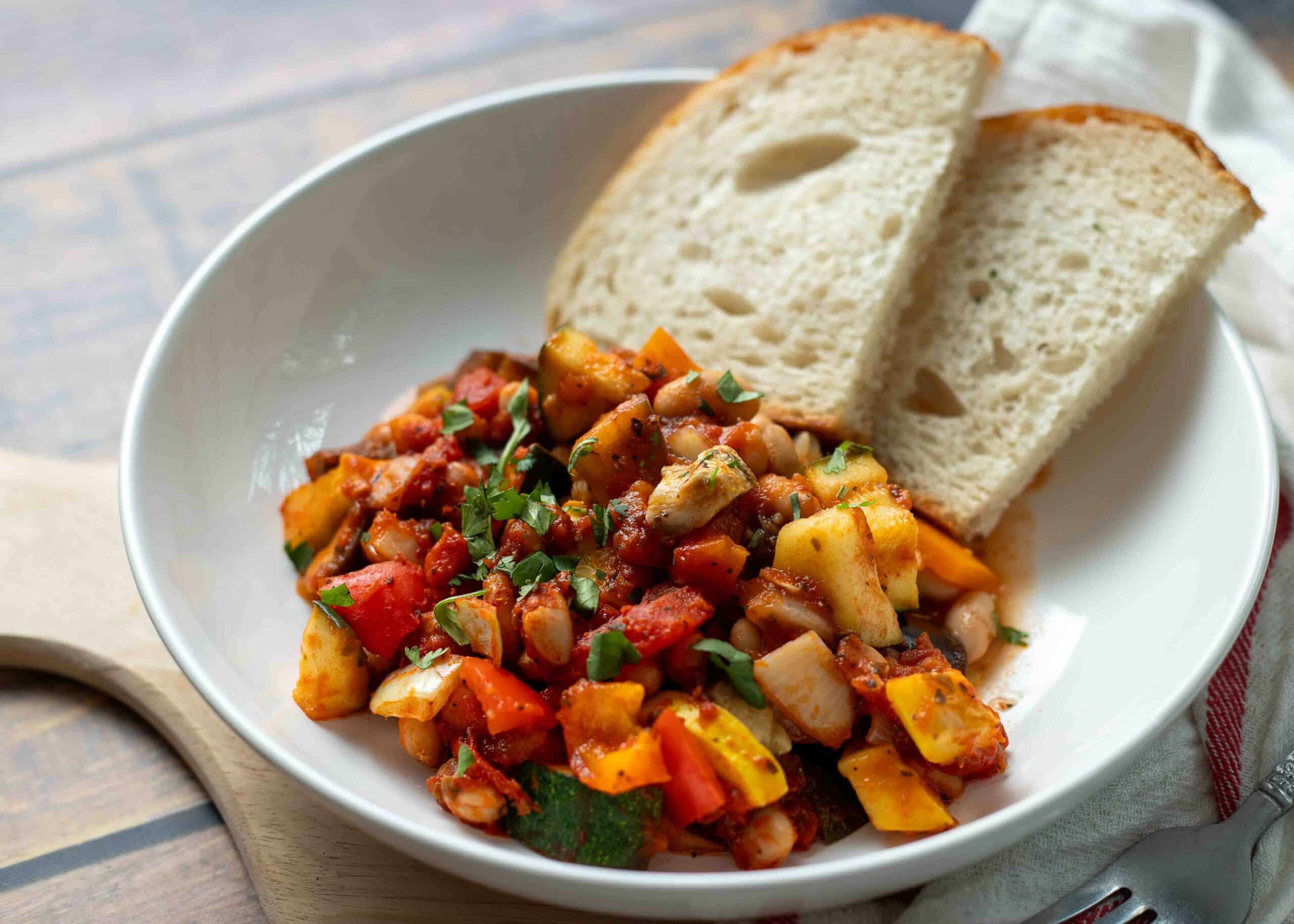 Ratatouille in a bowl served with slices of sourdough bread.