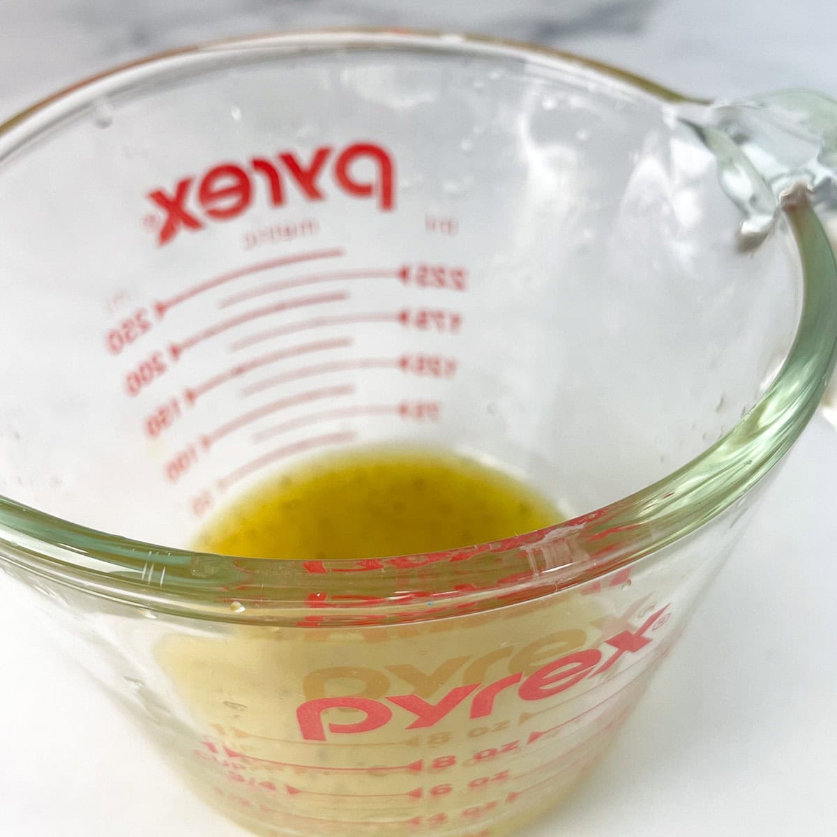 Lemon vinaigrette in a glass measuring cup.
