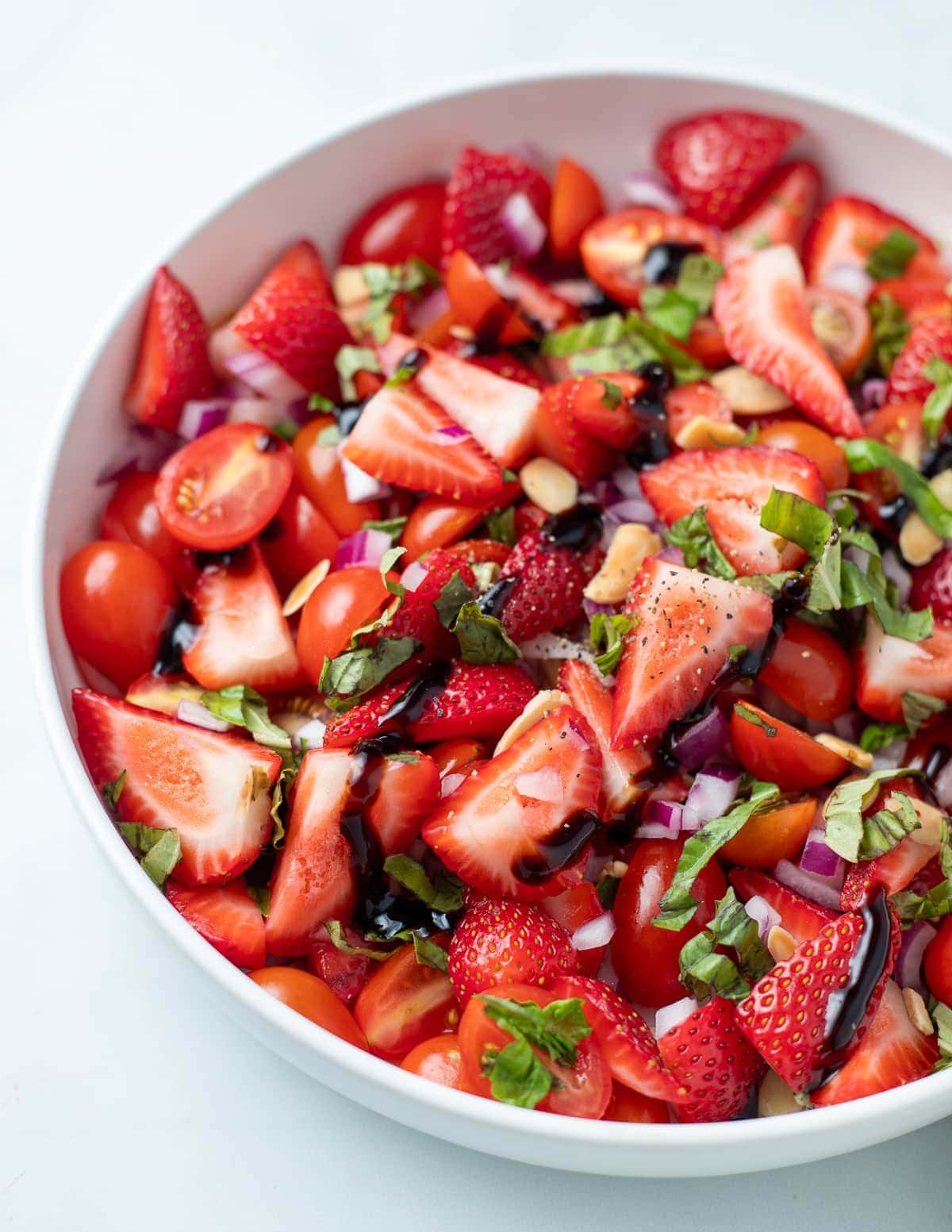 Strawberry and tomato salad topped with balsamic reduction and fresh basil.