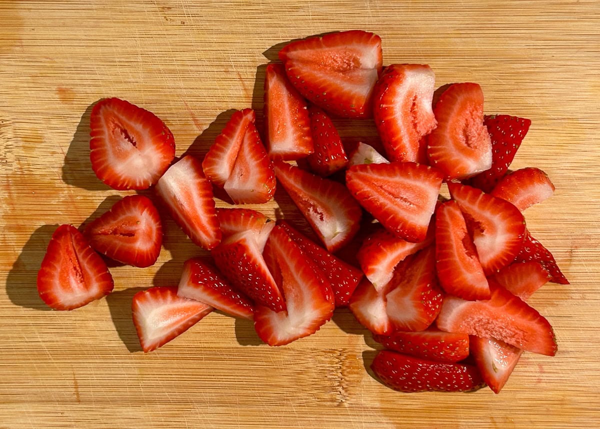 Sliced strawberries on a cutting board.
