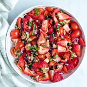 Strawberry and tomato salad in a white bowl.