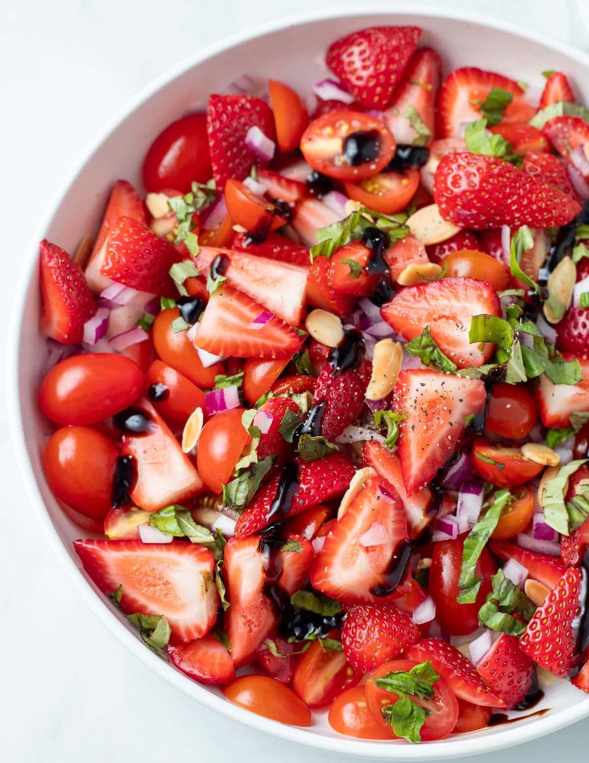 Strawberry tomato salad in a white bowl.