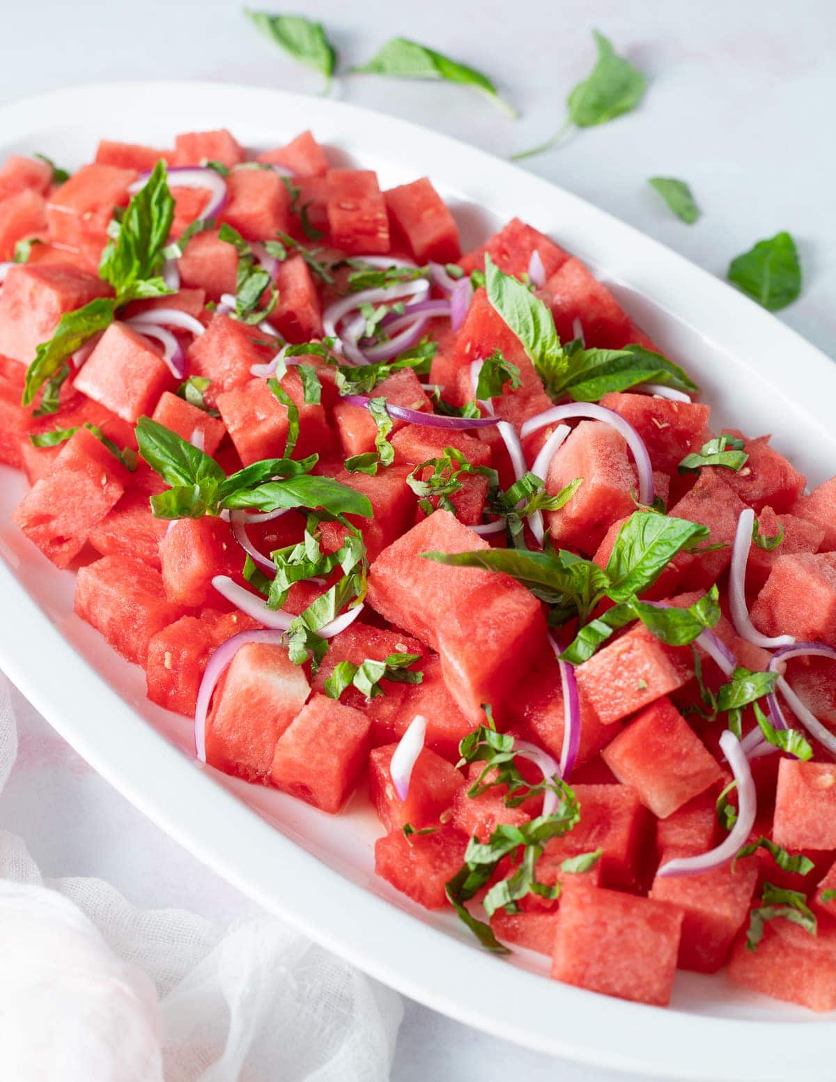 Watermelon basil salad on white serving platter.
