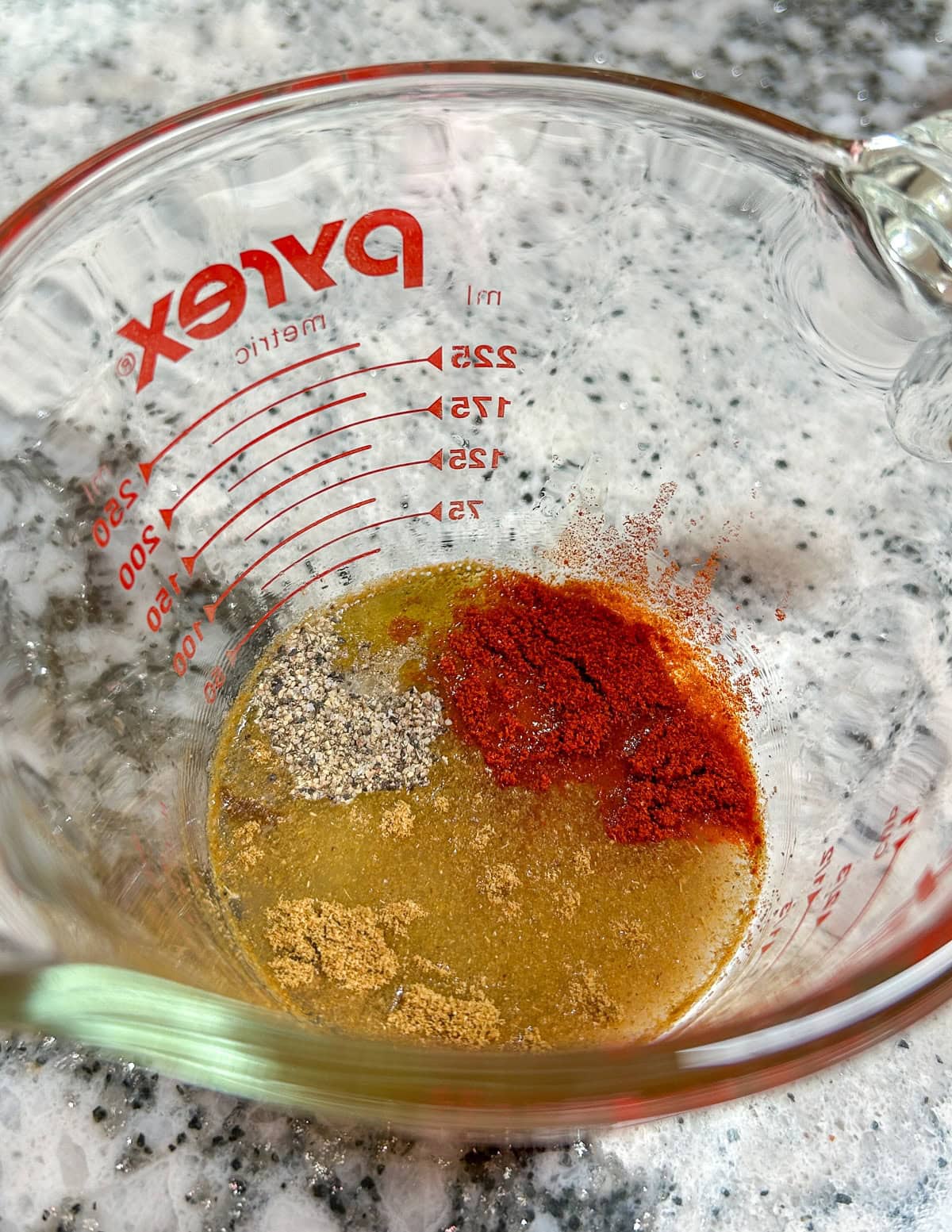 Lime dressing ingredients in a small glass measuring cup.