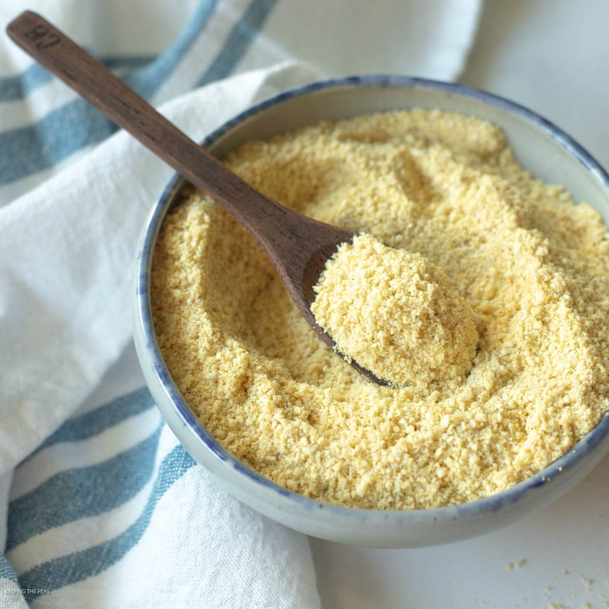Vegan parmesan cheese in small bowl with a serving spoon.