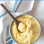Vegan parmesan cheese in a small bowl with a serving spoon.