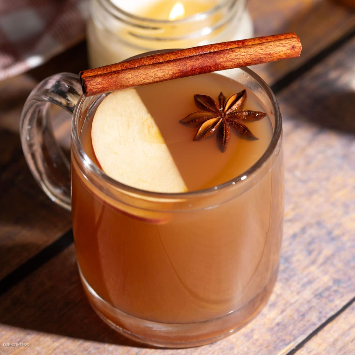 Hot apple cider cocktail in a glass mug served with an apple slice, cinnamon stick, and star anise.