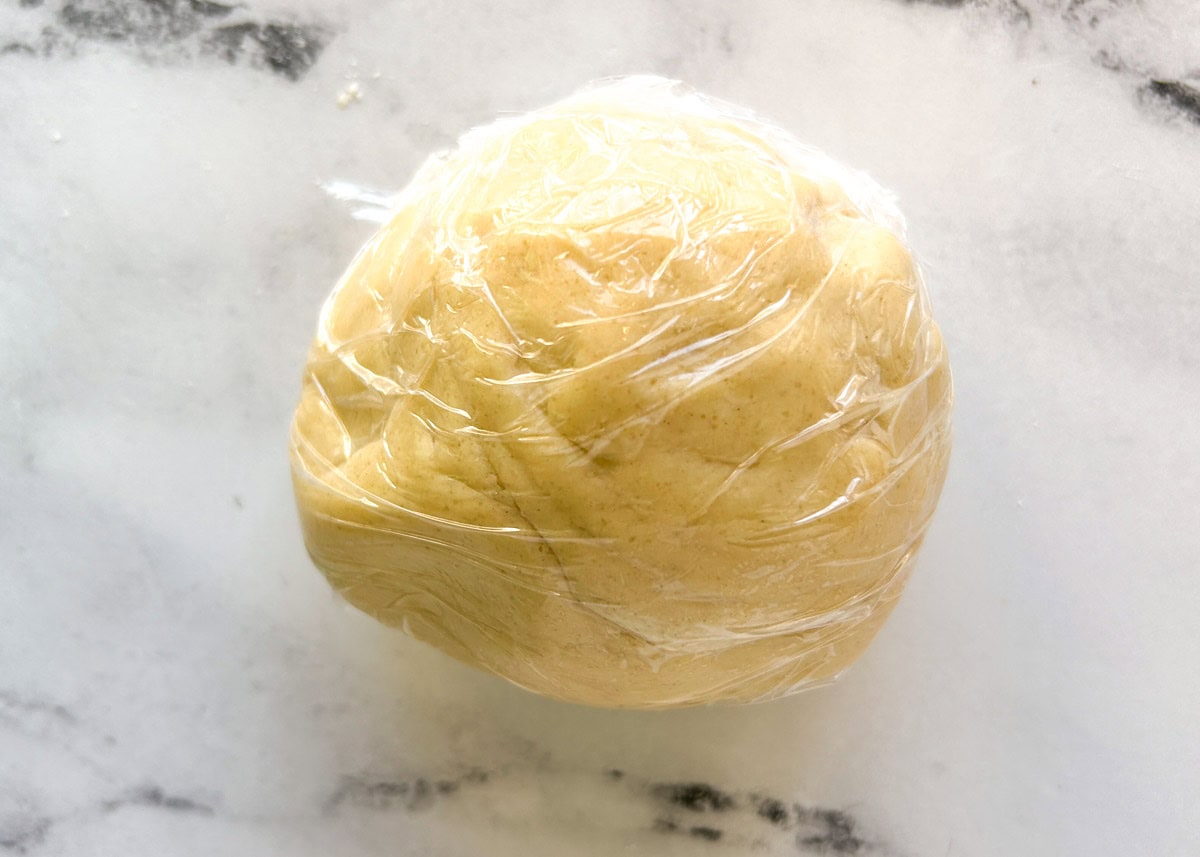 Pie crust dough formed into a ball and wrapped in plastic wrap.