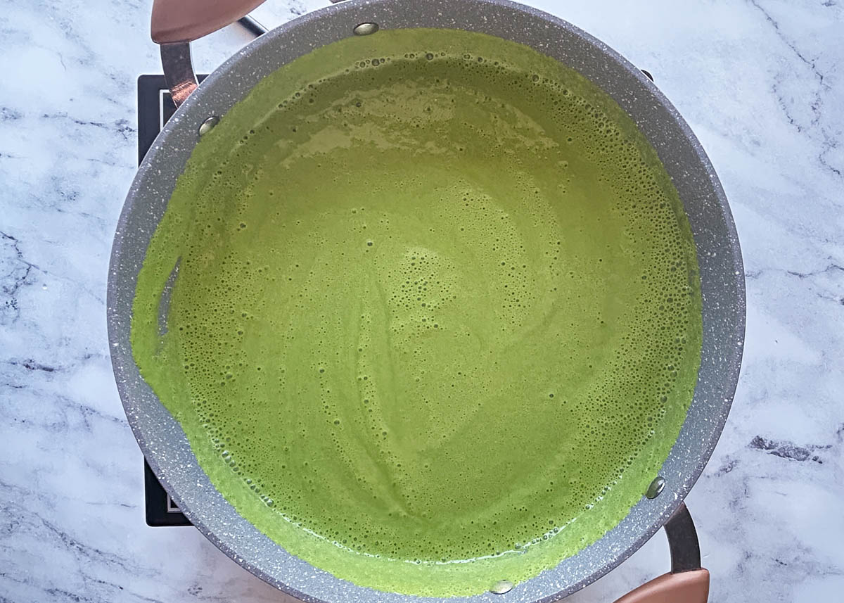 Green pasta sauce in saucepan.
