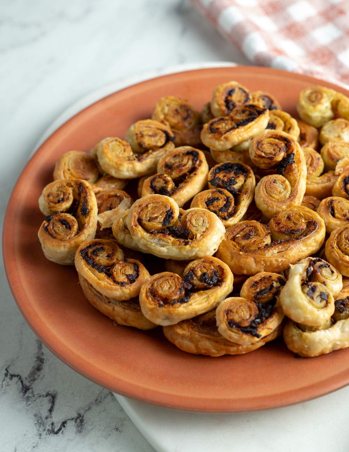 Savory palmiers with sun-dried tomato and pesto on an orange plate.