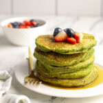 Stack of spinach banana pancakes topped with fresh berries.